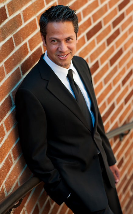 Dr. Paydar in black suit leaning against wall